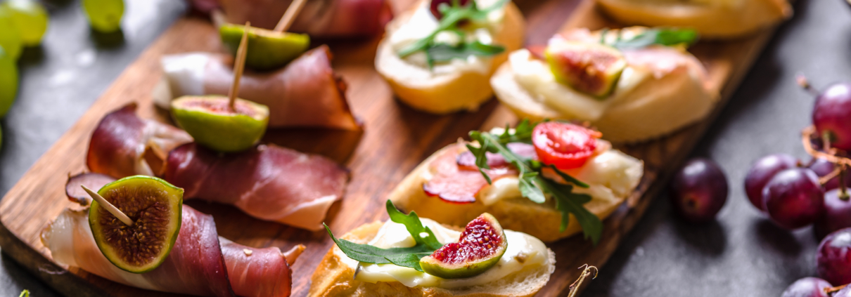Assorted brushetta - italian apetizer or traditional spanish tapas for sharing. Party food on catering platter. Antipasti with meat, cheese and fruits.